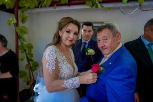 A joyful wedding celebration shows dancing and embracing between attendees in formal attire.