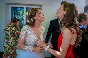 Wedding guests in formal attire share an animated conversation at an indoor reception.