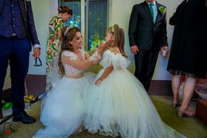 Two people in white tulle dresses share a joyful moment during a wedding celebration.