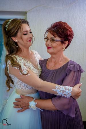 A heartfelt embrace between two wedding attendants in white and purple formal wear.