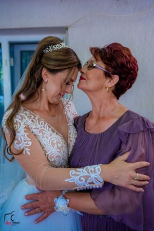 An intimate moment shared between wedding attendants in white lace and purple attire.