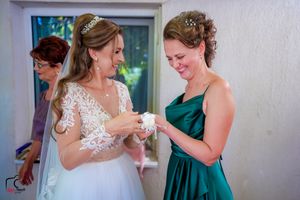 Wedding attendants share a tender moment while looking at something in their hands.