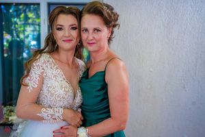 Two wedding party members pose together in white lace and emerald satin dresses.