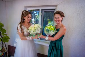 Wedding party in coordinated dresses of white, red and emerald green pose together.