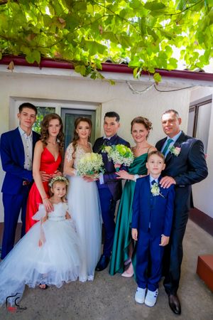 Wedding group photo showing attendees in formal attire including blue suits and colorful dresses.