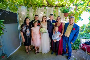 Wedding party group shot with decorative garden backdrop and white draping.