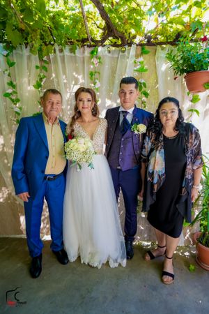 Wedding celebration group photo with floral decorations and natural lighting.