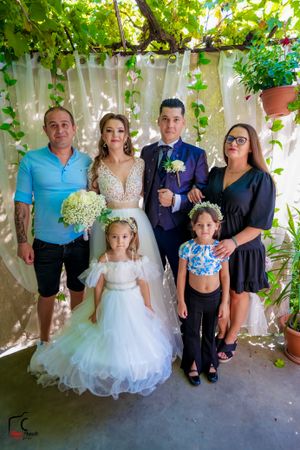 Wedding group photo under vine-covered pergola with white drapery.