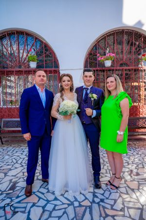 Wedding group poses with mix of formal attire including navy suit and bright green dress.