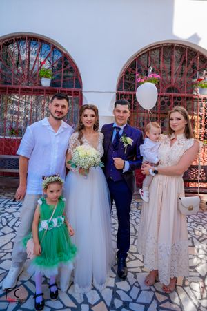 Wedding party members in mix of formal wear gather for photos outside church.
