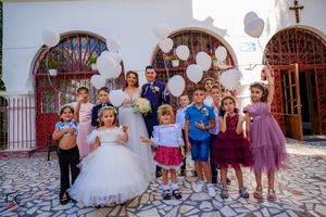 Wedding guests gather for group photos on stone patio with decorative red archways.