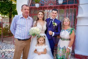 Wedding party members gather for formal portraits against white wall with ornate red metalwork.