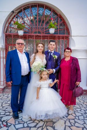 Wedding group poses in front of arched doorways with decorative iron grilles.