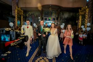 Wedding celebration in a grand ballroom with blue carpet and decorative gold trim.