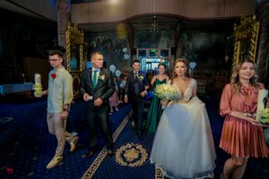 Elegant ballroom wedding reception with guests in formal attire and ornate gold decor.