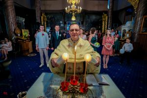 Religious ceremony in traditional church with golden decor and blue carpeting.
