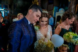 A wedding couple participates in a traditional ceremony in a beautifully lit church setting.