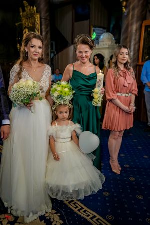 Wedding party members in emerald green and coral dresses with floral arrangements.