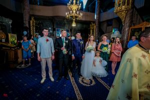 Wedding party members standing in a traditional church setting with decorative lighting.