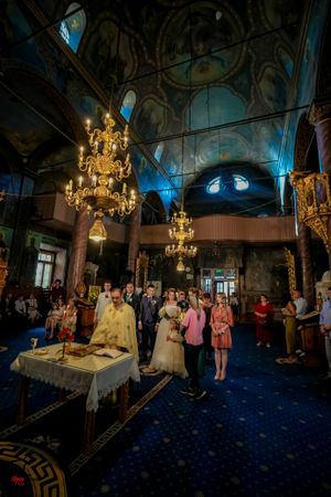 Wedding guests gathered in a dimly lit church interior with golden chandeliers.