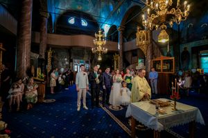 Elegant wedding ceremony in a church with ornate chandeliers and blue carpeting.