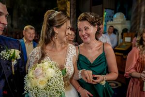 Wedding celebration scene with elegant dresses and floral bouquets in an indoor venue.