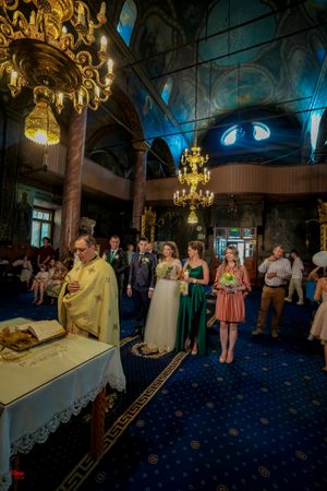 Wedding ceremony venue features golden chandeliers and dramatic blue ambient lighting.
