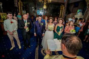 Wedding guests gather in an ornate venue with blue carpeting and golden chandeliers.