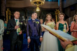 Wedding party gathers under ornate chandeliers in an elegant venue with golden lighting.