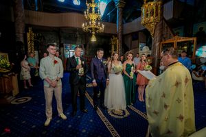 Wedding ceremony in ornate church interior with priest and attendees.