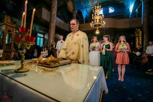 Priest preparing communion elements at altar during Orthodox church ceremony.