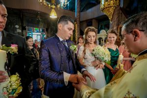 Wedding ceremony with couple receiving blessings from priest in ornate church setting.