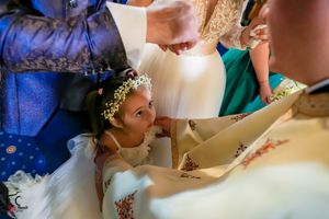Young flower girl in white dress participating in wedding ceremony.