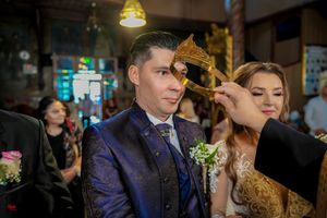 Ceremonial crowning ritual being performed on couple during Orthodox wedding.