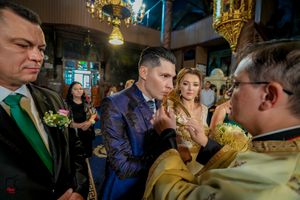 Wedding ceremony participants gather in a church with ornate decorations and lighting.