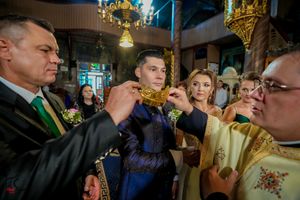 Traditional Orthodox wedding crowning ceremony with multiple participants in church setting.