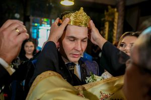 Golden crown being placed during traditional Orthodox wedding ceremony in church setting.