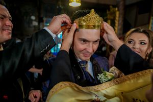 Traditional Orthodox wedding crowning ceremony with ornate golden crown being placed.