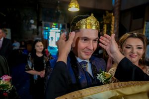 Wedding ceremony participant adjusts ceremonial crown during Orthodox Christian ritual.