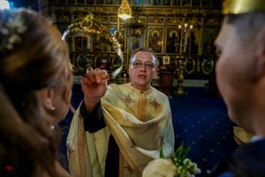 Ornate Orthodox church interior with golden details and religious iconography during ceremony.