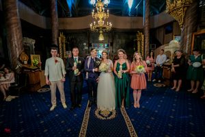 Wedding celebration in grand ballroom with ornate decor and dramatic blue lighting effects.