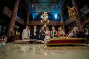Wide angle shot of wedding celebration in grand hall with decorative columns and chandeliers.