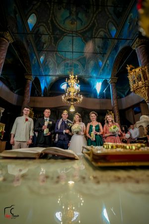 Wedding reception venue with blue uplighting and elegant chandeliers showing party members behind decorated table.