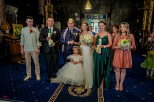 Wedding group photo with flower girl in white dress and attendants in colorful attire.