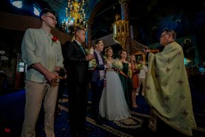 Wedding ceremony guests gather in an elegant venue with chandeliers and blue lighting.