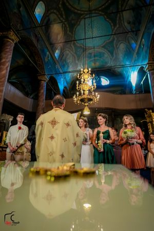 Wedding ceremony in historic church with dramatic lighting and traditional Orthodox decorations.