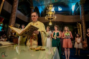 Orthodox church wedding ceremony with elegant chandelier lighting and decorative architecture.