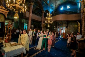 Wedding celebration in historic church with dramatic blue lighting and golden chandeliers.