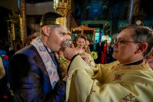 Wedding celebration in an Orthodox church with clergy wearing traditional gold vestments.