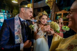 Wedding ceremony participants gather in an Orthodox church with ornate golden decorations.